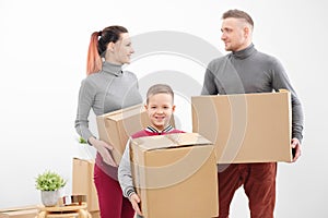 Young family, man woman and child son in new apartments. Carried in the hands of cardboard boxes. Boxes with cargo on a
