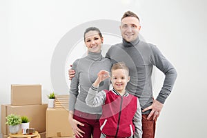 Young family, man woman and child son in new apartments. The child holds the keys to the apartment. Boxes with cargo on