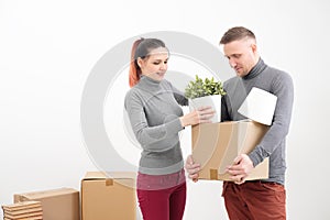 A young family, a man and a woman in gray sweaters are moving to a new apartments. Boxes with cargo on a white