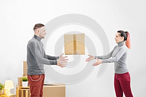 Young family, man and woman in new apartments throw each other a box.. Boxes with cargo on a white background.