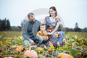 Young family, mom, dad and little boy spending time at the pumpkin`s farm. Fall time. American holidays - Halloween and