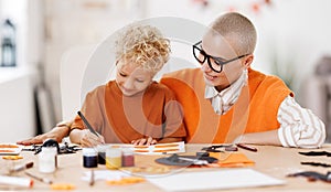 Young family mother and child preparing decorations for Halloween and engage in creativity