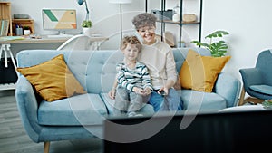 Young family mother and child watching TV talking and laughing indoors at home