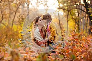 Young family, mother and little son, on walk in autumn forest, mom and child holding hands and walking along path covered with