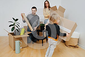 Young family moved into a new home, unpacking cardboard boxes together