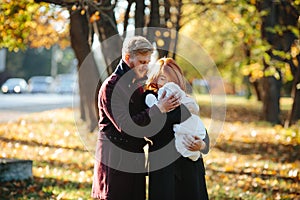 Young family and newborn son in autumn park