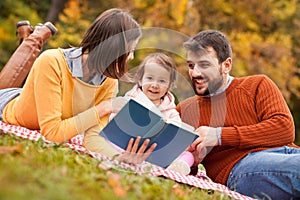 Young family outdoor on picnic with book