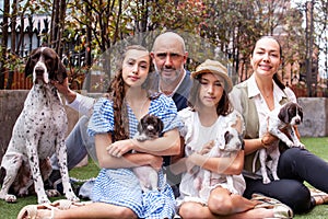 Young family outdoors with their newborn puppies in a sunny day