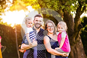 Young family outside in sunny summer park, green nature