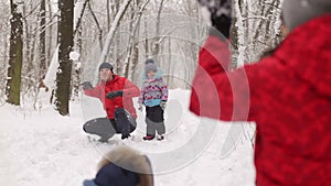 Young family play in the snow in winter Park.