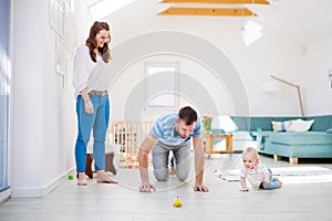 Young family playing with a baby boy at home.