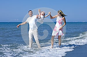 Young family playing with daughter on beach in Spain