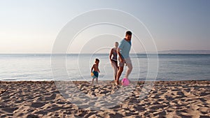 Young family playing football on the beach