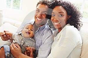 Young Family Playing With Happy Baby Son At Home