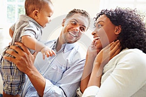 Young Family Playing With Happy Baby Son At Home