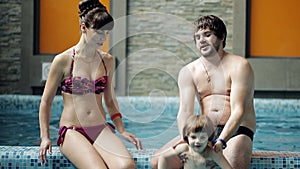 Young family in the pool. Parents with son swim and play in the pool.