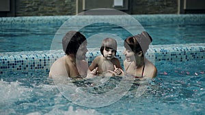 Young family in the pool. Parents with son swim and play in the pool.