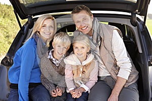 Giovane famiglia posa comune sul posteriore da auto 