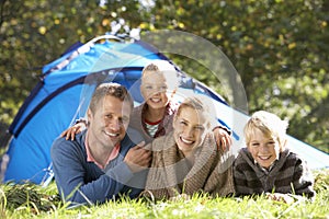 Young family poses outside of tent