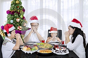 Young family praying before Christmas dinner