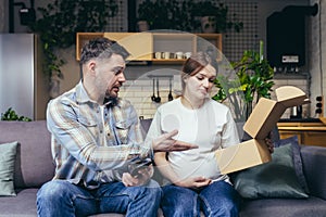 A young family, a pregnant woman and a man accidentally received someone else`s parcel. They opened the box, disappointed. Sittin