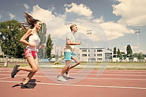 Young family promoting healthy lifestyle. Woman and man run stadium. Coach and sportsman motion run training before race