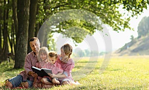 Young family reading the Bible in nature