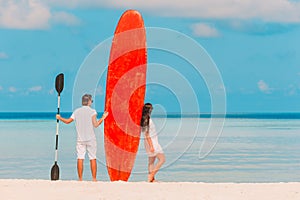 Young couple with red surfboard during tropical vacation