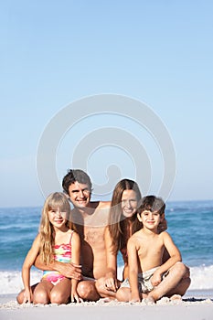 Young Family Relaxing On Beach Holiday