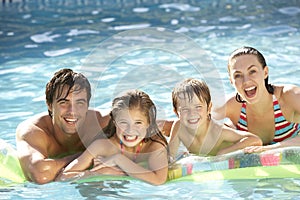 Young Family Relaxing In Swimming Pool