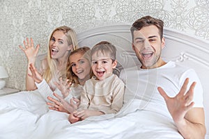 young family relxing in bed together