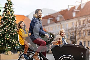 Young family riding in a cargo bicycle during Christmas