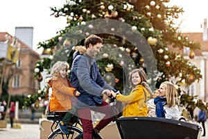 Young family riding in a cargo bicycle during Christmas