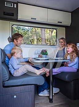 A young family seated at the dining table in a modern Australian Caravan
