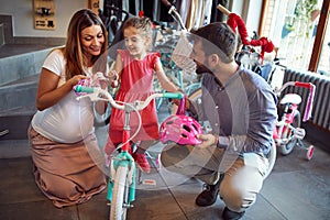 Young family shopping new bicycle for little girl in bike shop