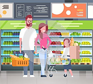 Young Family Shopping At Supermarket And Buying Products Over Shelves At Grocery Consumerism Concept