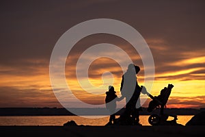 Young family silhouetted against an ocean sunset