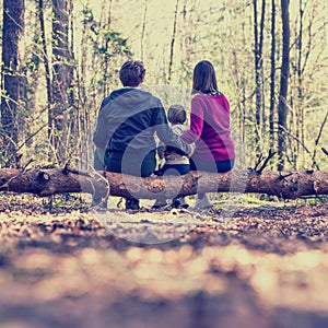 Young family sitting on a tree trunk