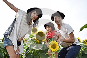 young family is smiling with sunflower field