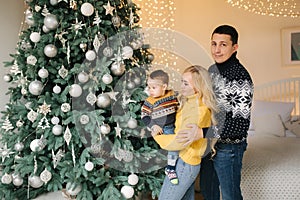 Young family spend time at home in Christmas time. Happy Mom, dad and son enjoyng love hugs, holidays people