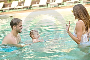 A young family spending time in a summer swimming pool