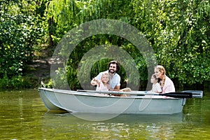 young family spending time together in boat on river at park