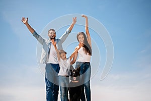 Young family standing together with dog and smiling at camera outdoors