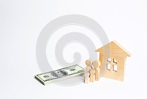 A young family stands near a wooden house and with a bundle of money. The concept of a strong family, the continuation