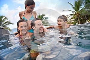 Young family in swimming pool spending good time