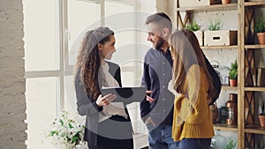 Young family is talking to housing agent inside new flat about purchasing real estate, hugging and gesturing emotionally