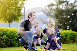 Young family with their toddler children blowing soap bubbles
