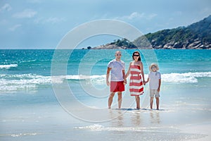 Young family of three having fun tropical beach