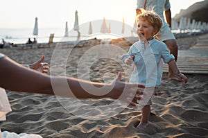 Young family with toddler boy having fun on beach on summer holiday.