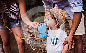 A young family with a toddler boy outdoors by the river in summer.